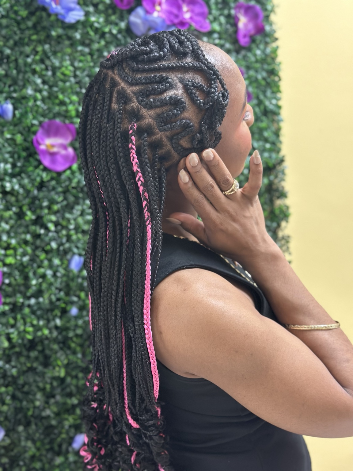 Rose Jolie curved braids with pink accents against a floral backdrop